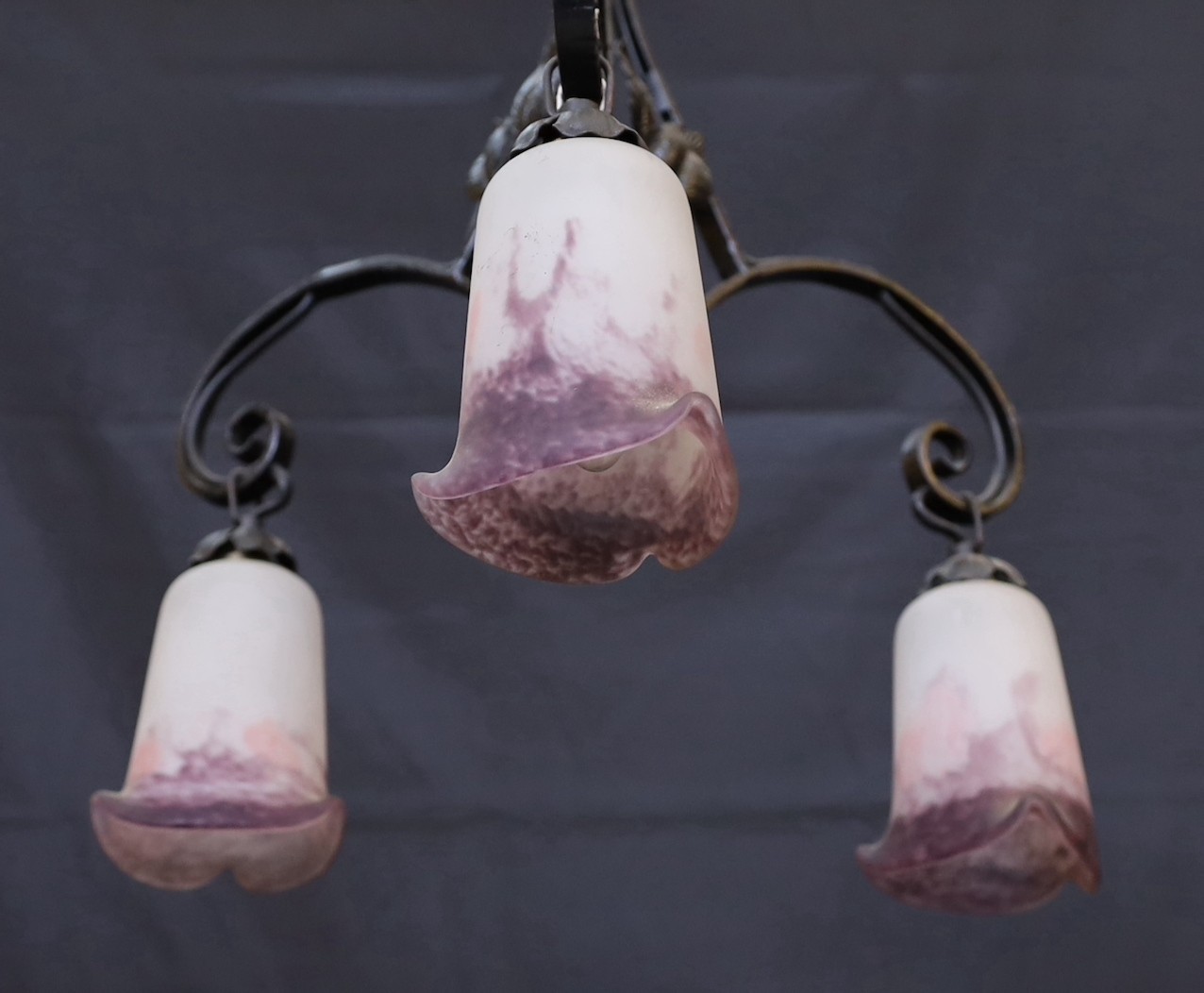 A 1920s French wrought iron three branch light fitting with marbled and frosted glass shades, height 74cm. width 43cm